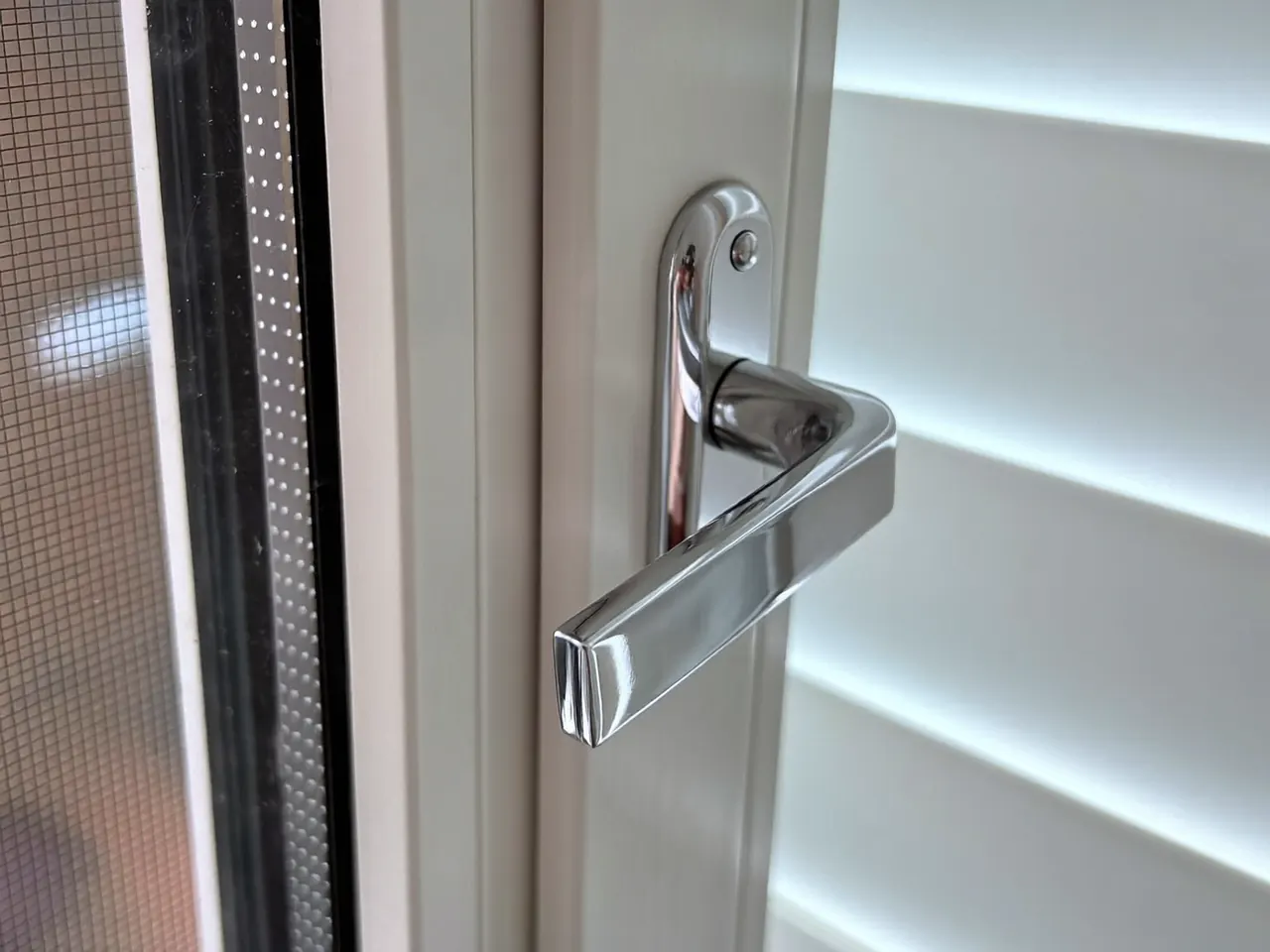 Polished chrome handle and multi-point lock on a white uPVC casement window
