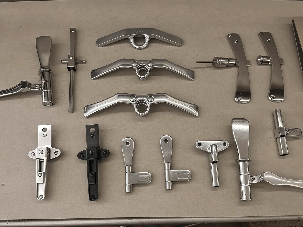 A selection of window handles, hinges and locks laid out for choosing